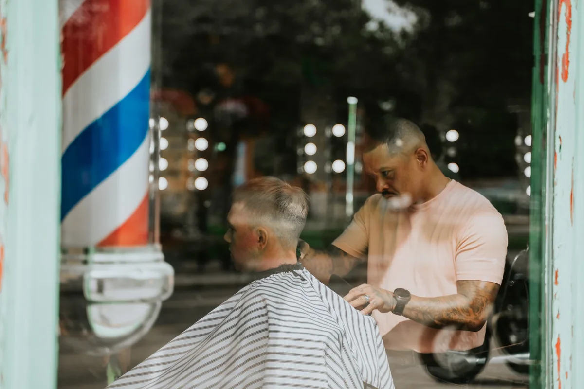 A barber cutting a customer’s hair in a Corydon Avenue barbershop