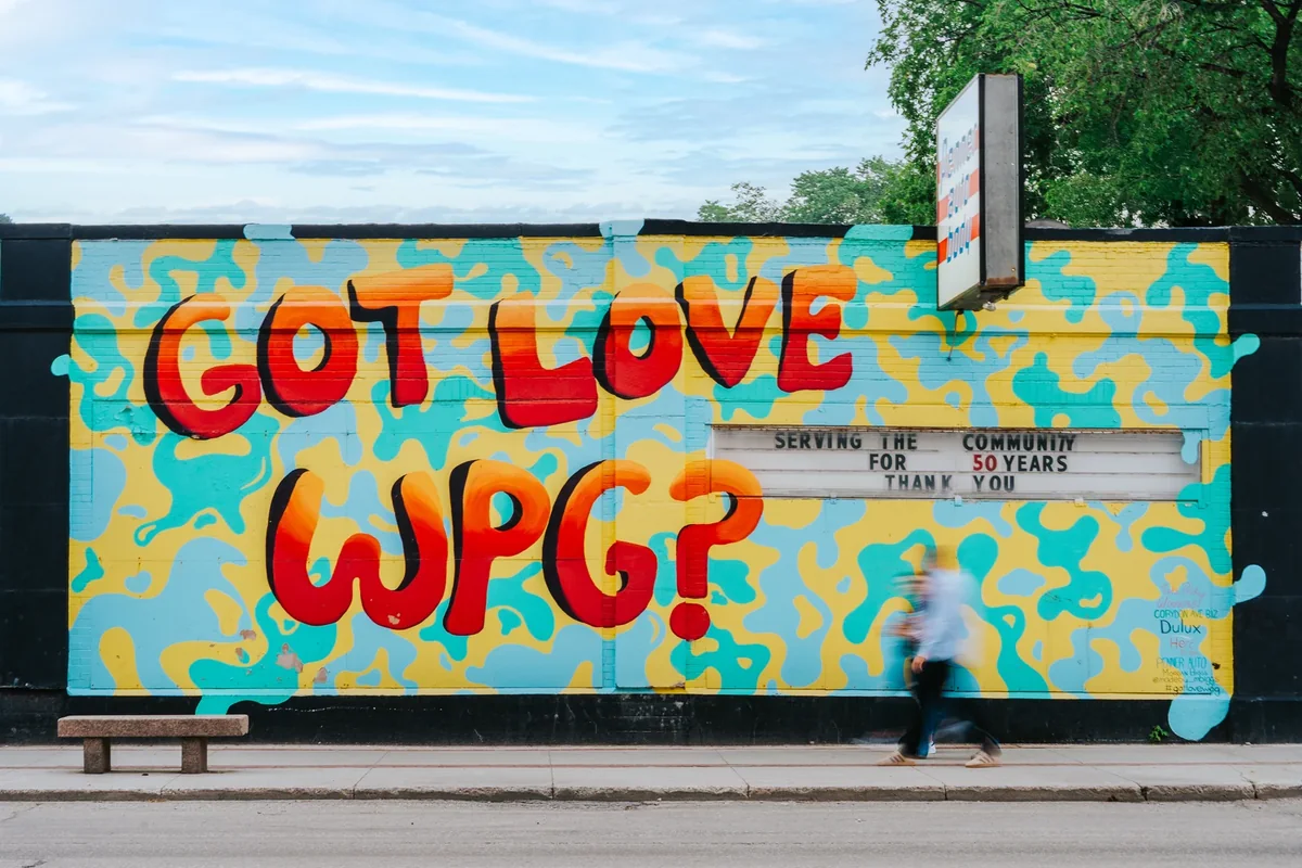 A pedestrian walking past the colourful Got Love WPG mural